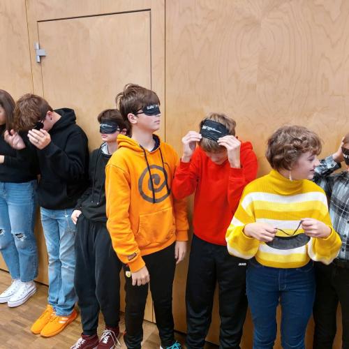 Schülerinnen und Schüler setzen sich Schlafmasken auf