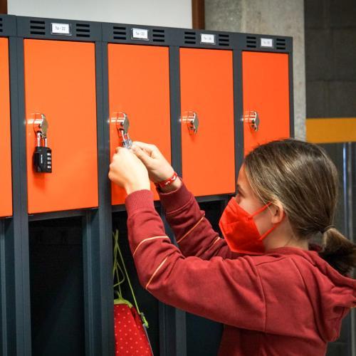Schülerin öffnet ihren orangen Spint