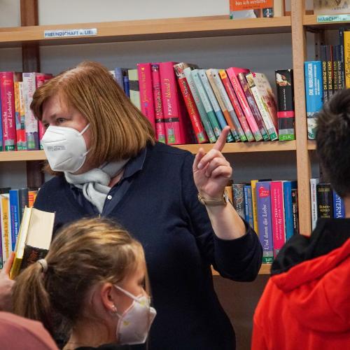 Lehrperson erklärt die Abläufe einer Bibliothek