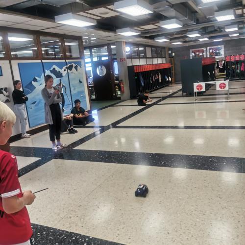 Kinder veranstalten ein Spielzeugautorennen in Schulhalle. 