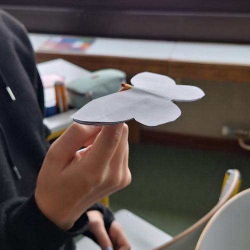 Selbstgebastelter Schmetterling wird im Schwerpunkt auf einem Finger balanciert.