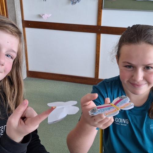 Selbstgebastelter Schmetterling wird im Schwerpunkt auf einem Finger balanciert.