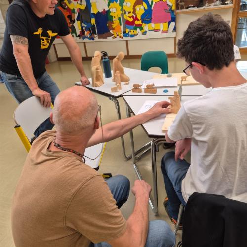 Bildhauer zeigt Schüler das Schnitzen