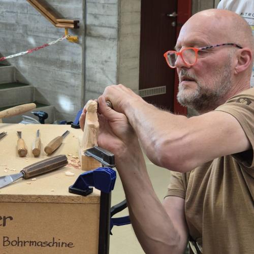Bildhauer zeigt Schüler das Schnitzen