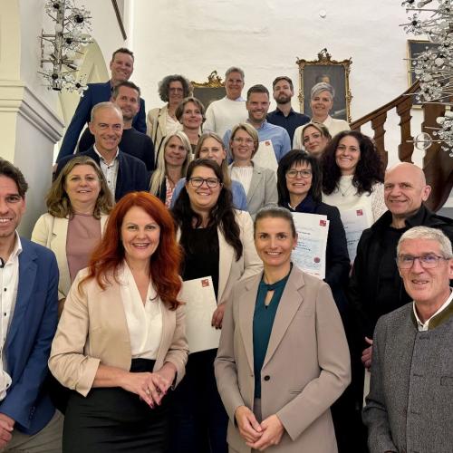 Menschen stehen auf einer Treppe, Gruppenfoto, schauen alle freundlich in die Kamera. 